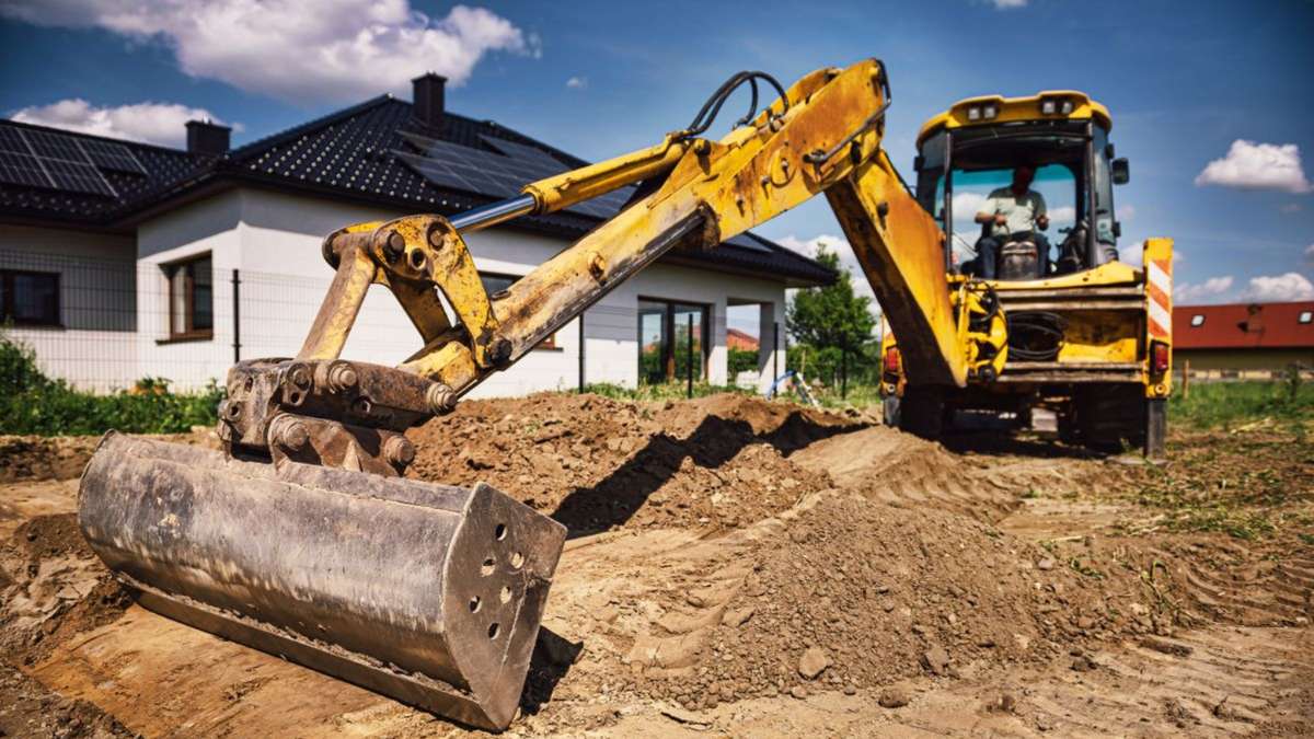 Pelleteuse chaury-tp à Toulouse creusant un terrain près d’une maison moderne avec panneaux solaires