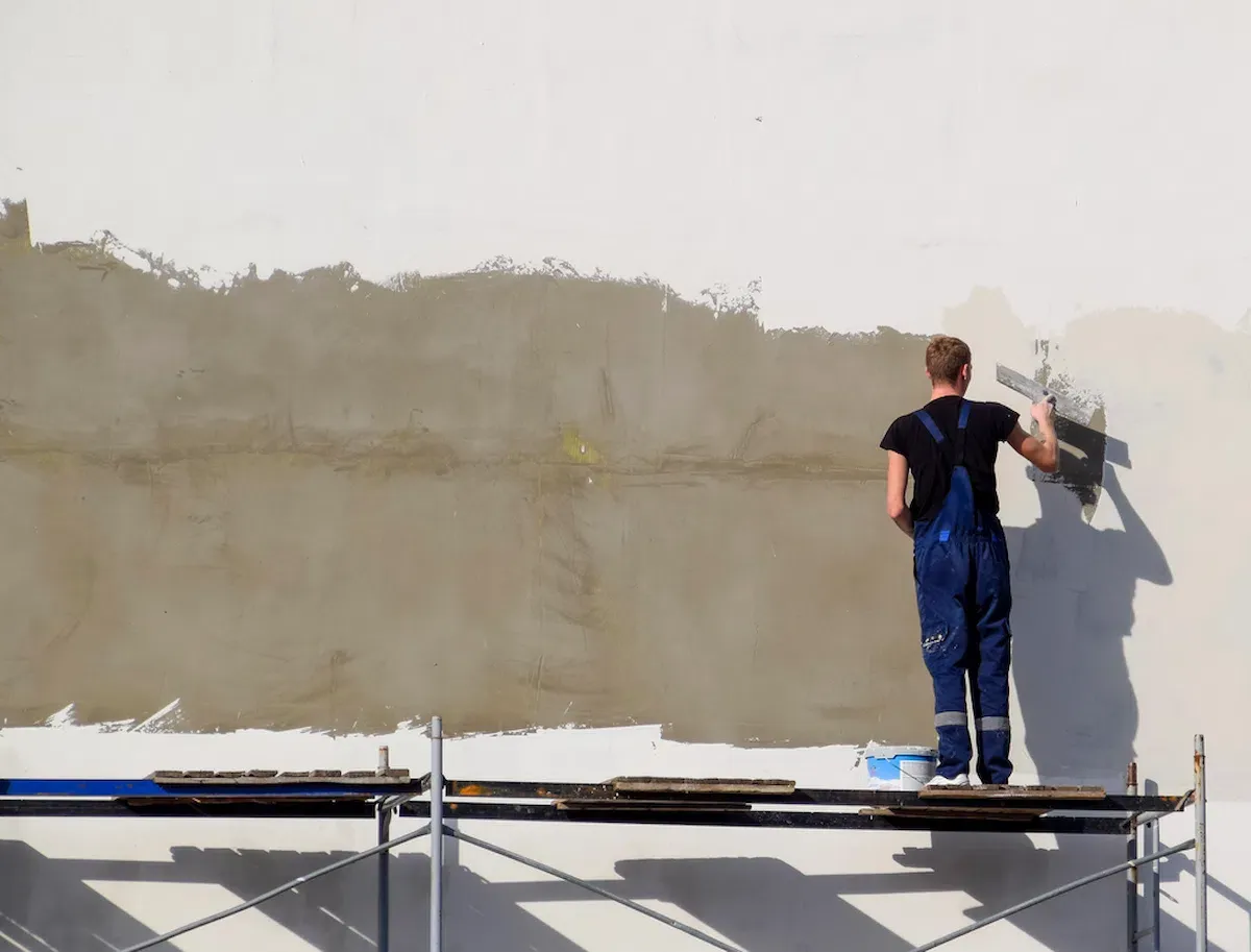 Artisan chaury-tp rénovant un grand mur extérieur sur échafaudage à Toulouse